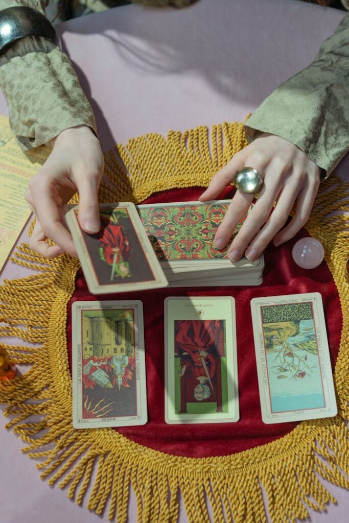 A mystical scene of a fortune teller's hands arranging tarot cards on a fringed cloth.